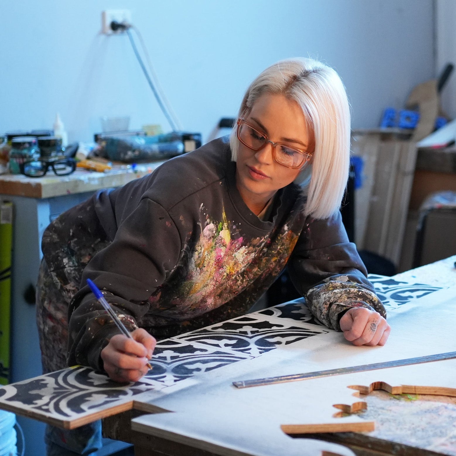 Person working on a craft project wearing Ugly Fish Safety glasses at a table with various materials and tools.