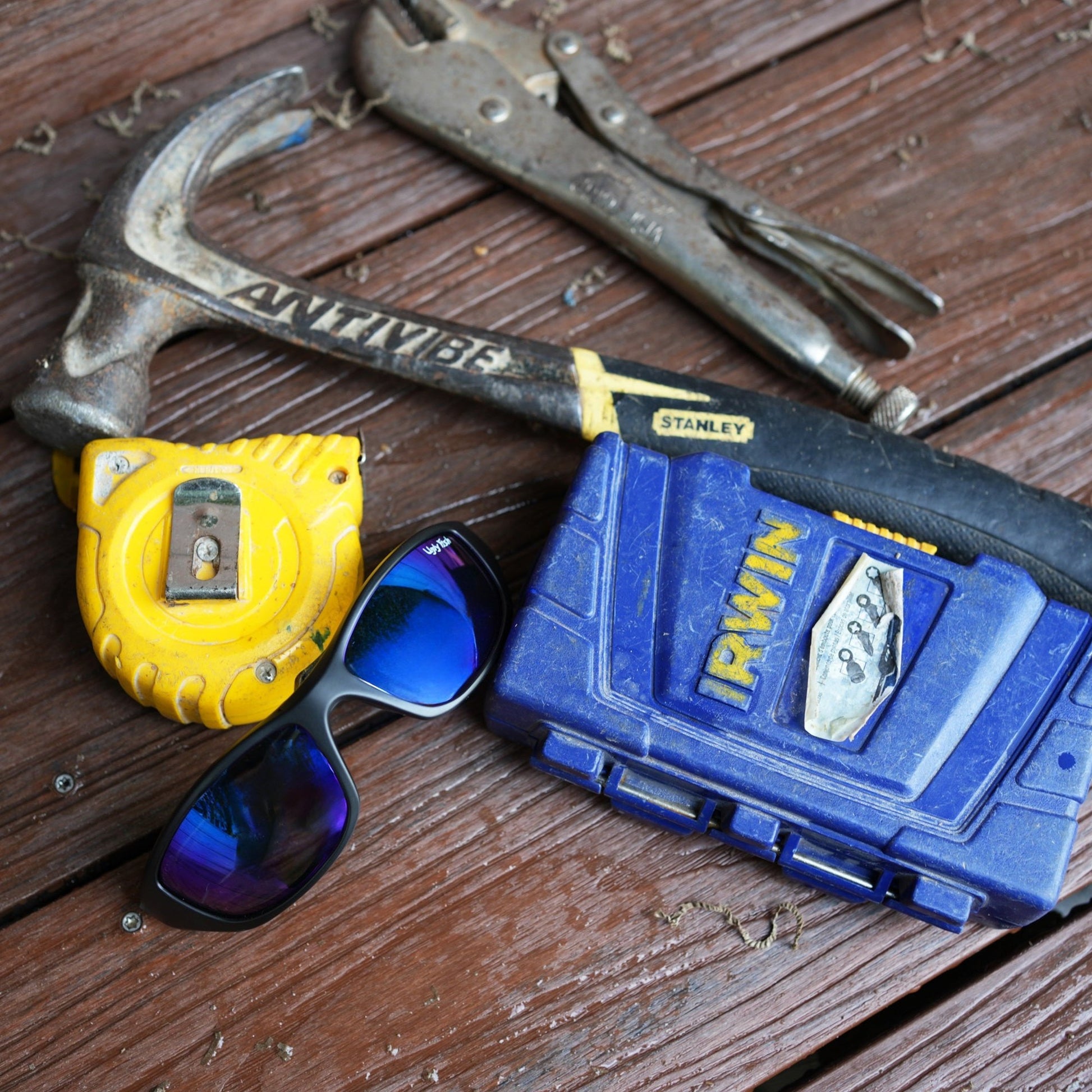 A pair of black Ugly Fish Sunglasses with blue lenses sit on a construction bench.