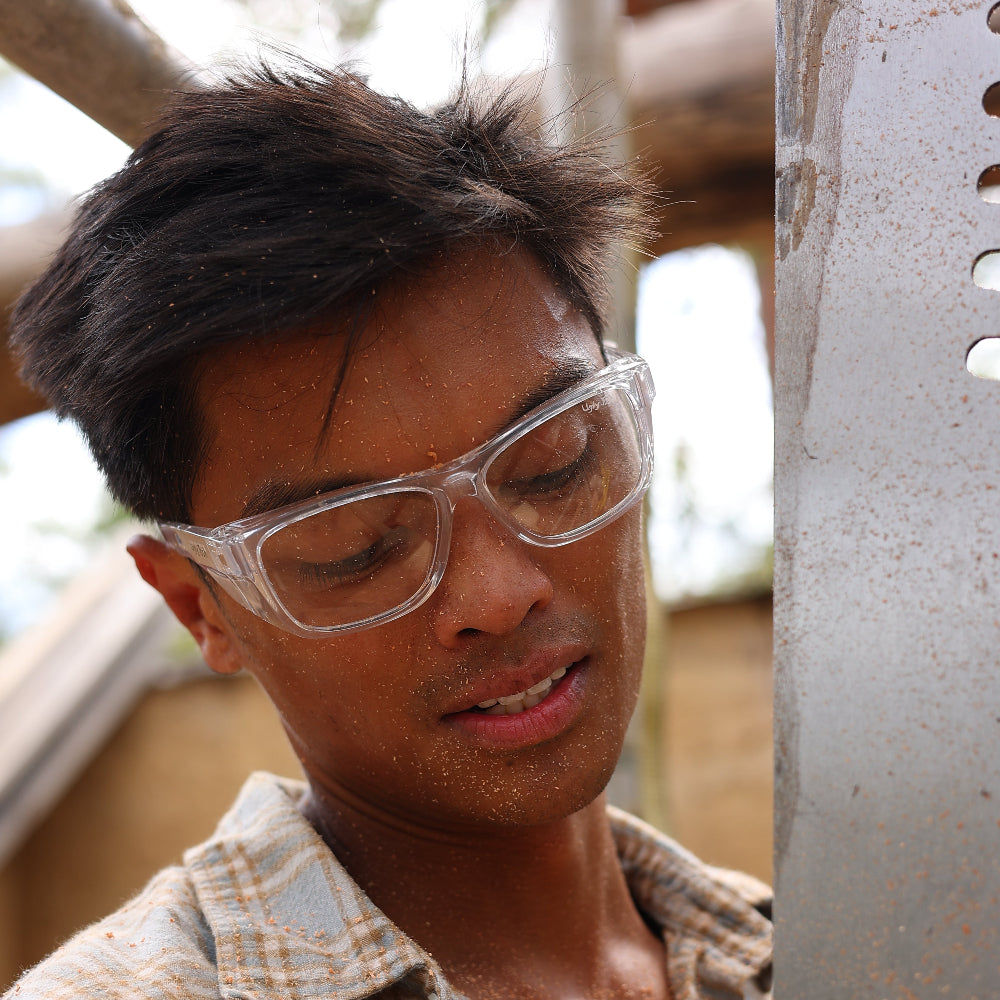 Person wearing Ugly Fish Safety sunnies and holding a wooden object, likely in a workshop setting.