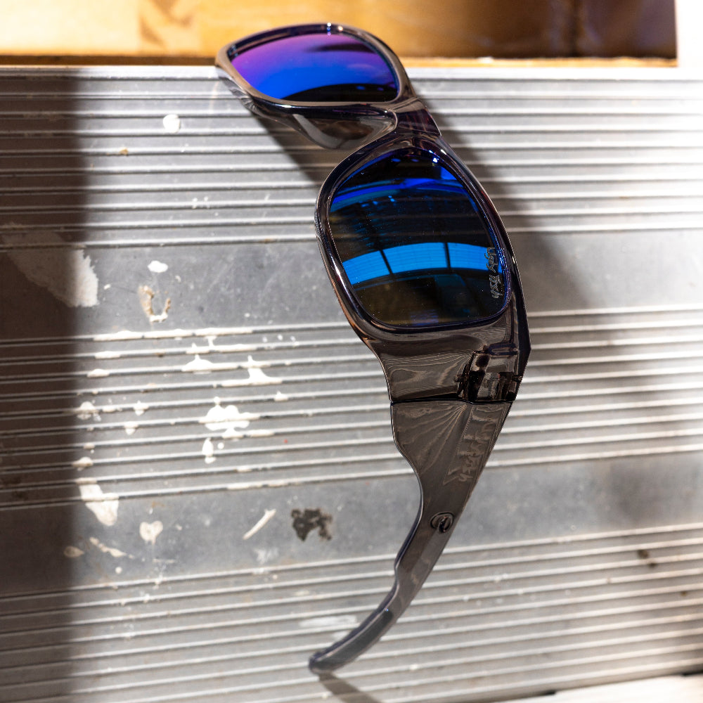 Ugly Fish Safety Sunglasses with blue reflective lenses on a metallic surface.