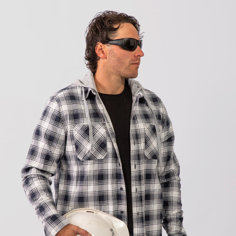 Man wearing a plaid shirt and Ugly Fish Safety sunglasses sunglasses holding a white helmet against a plain background