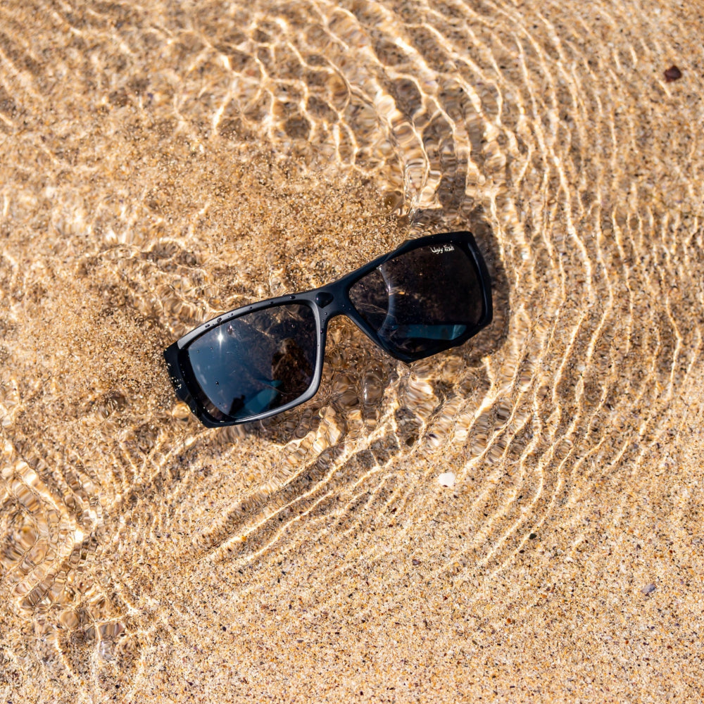 Ugly Fish floating sunglasses on wet sand with water droplets