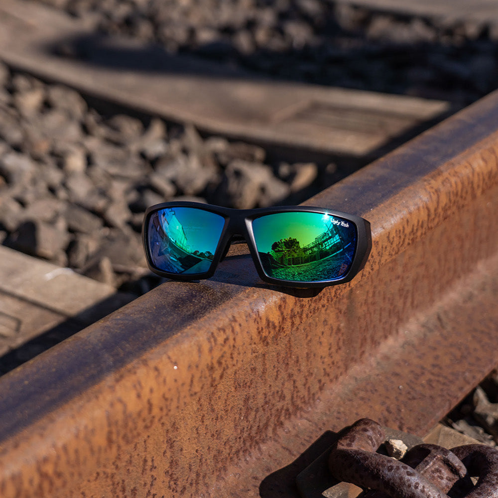 Ugly Fish Safety sunglasses with a mirror lenses on a rusted metal surface.