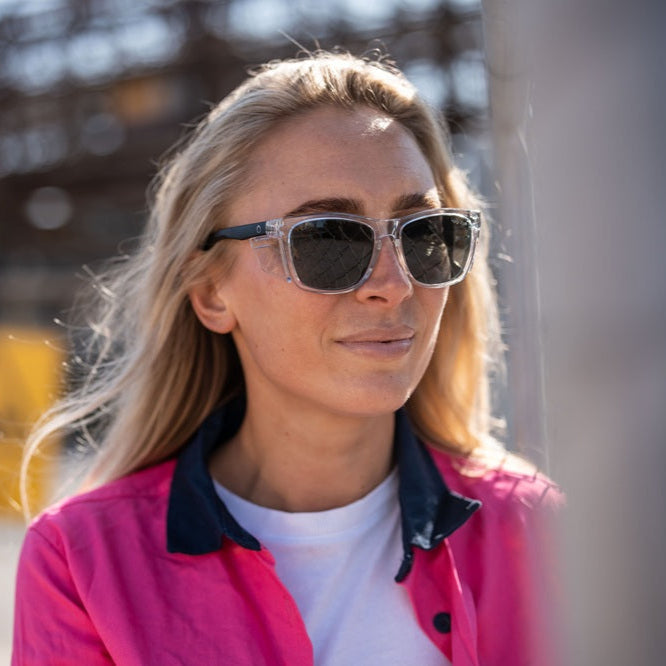 Woman wearing Ugly Fish Safety sunglasses and a pink jacket outdoors