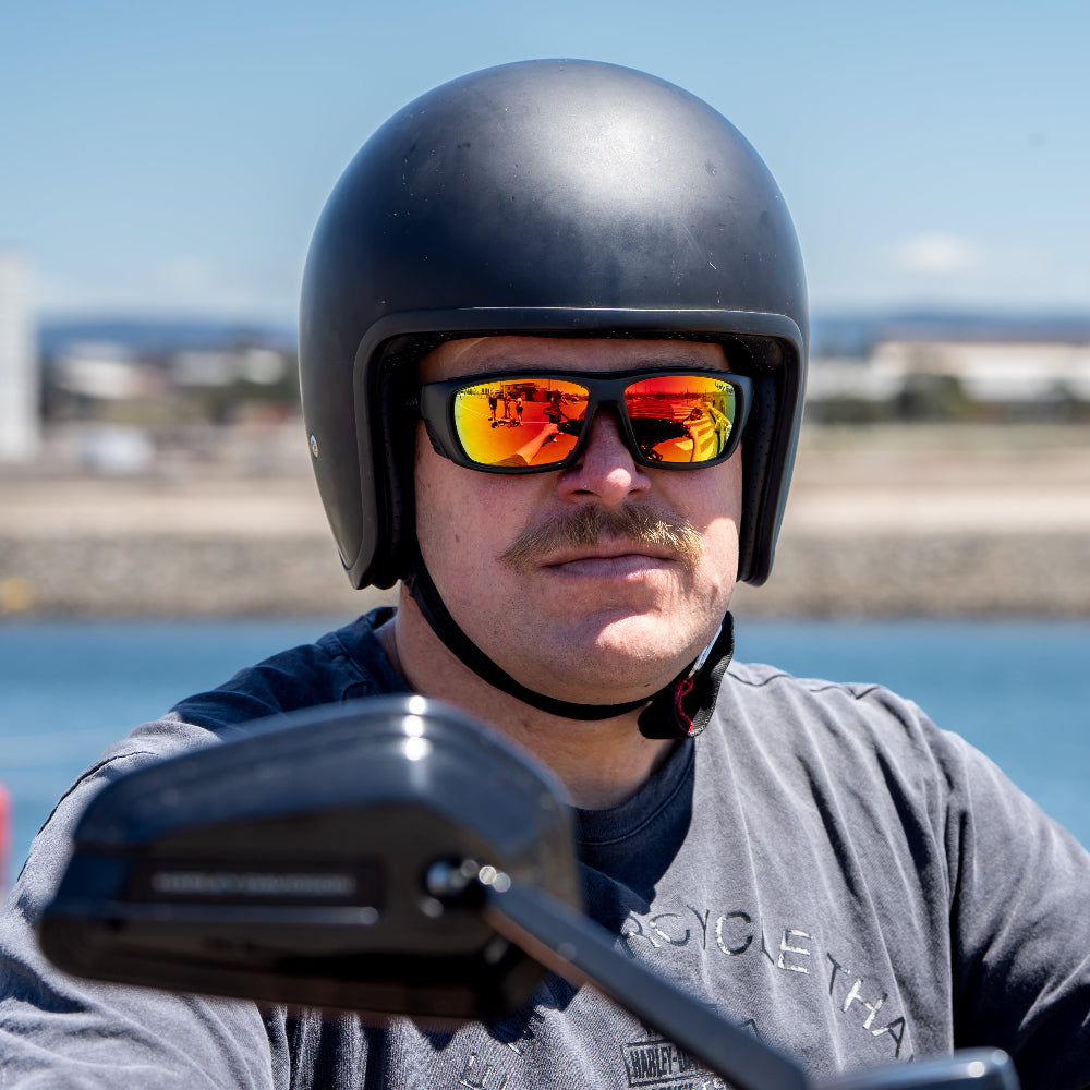 Man wearing a black helmet and reflective sunglasses with a blurred background