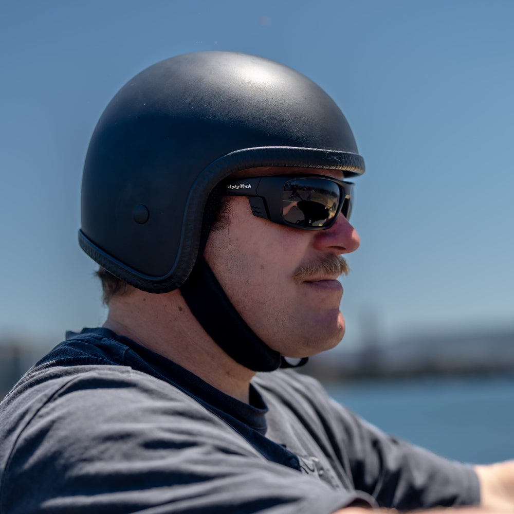 Man wearing a black helmet and sunglasses with a blurred background