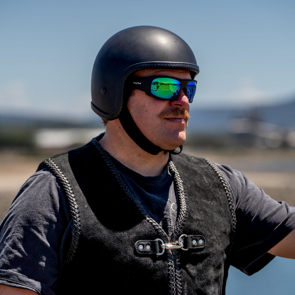 Person wearing a helmet and Ugly Fish motorcycle sunglasses with a blurred background