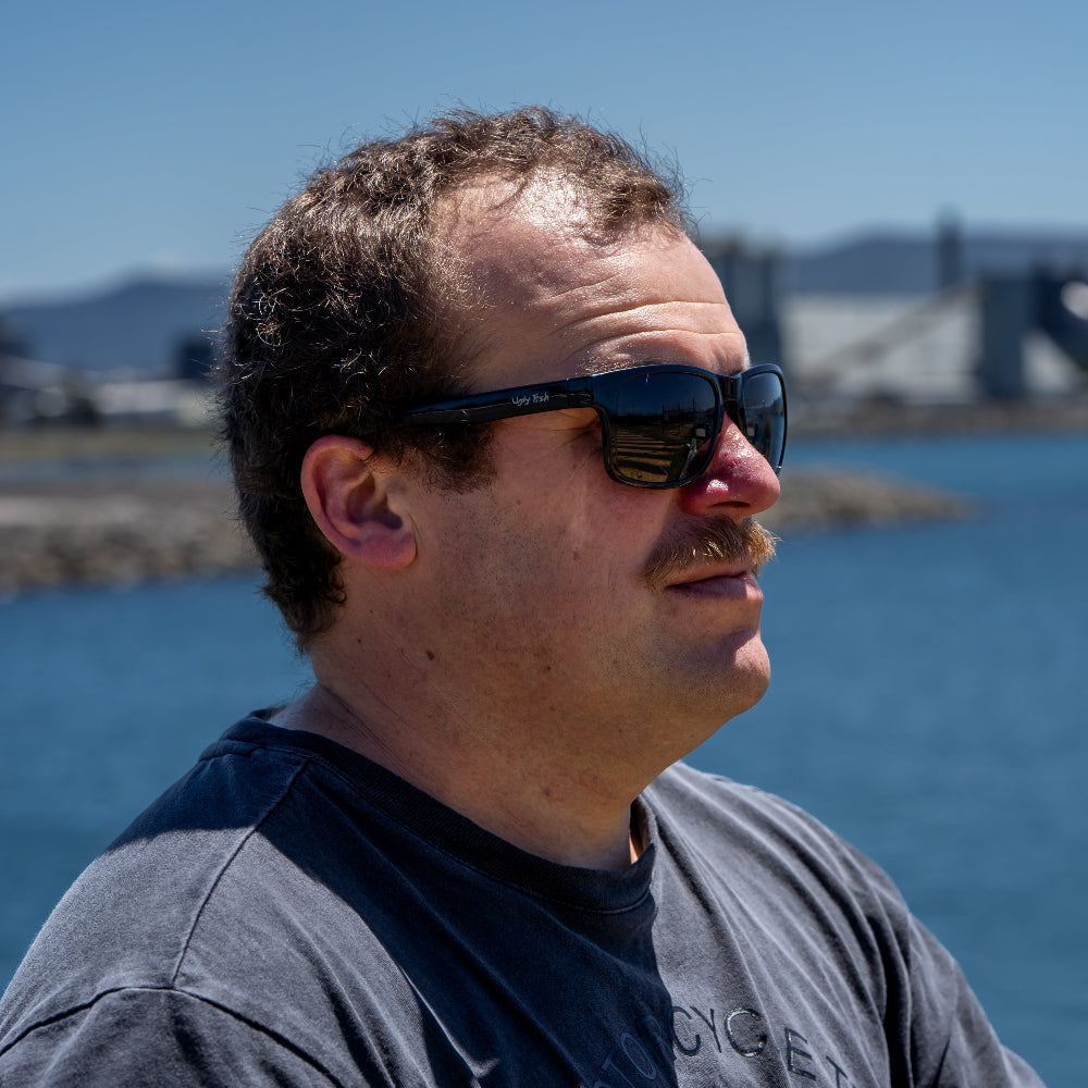 Man wearing Ugly Fish Unbreakable sunglasses with a blurred background of water and sky