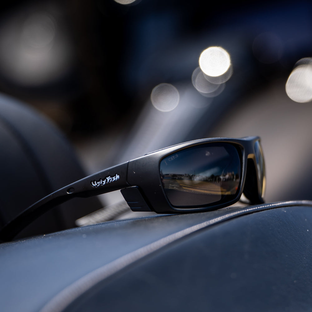 Black sunglasses on a car dashboard with blurred lights in the background