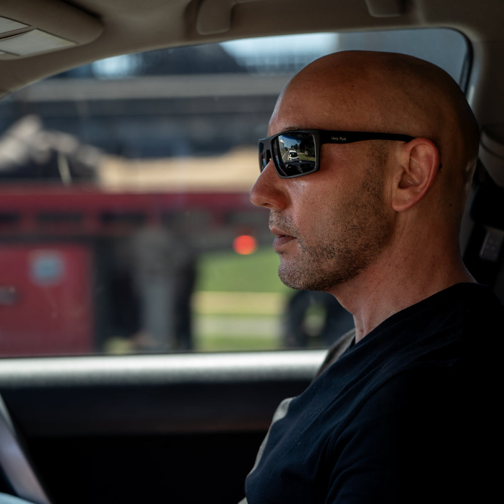 Man wearing sunglasses sitting inside a vehicle with a blurred background