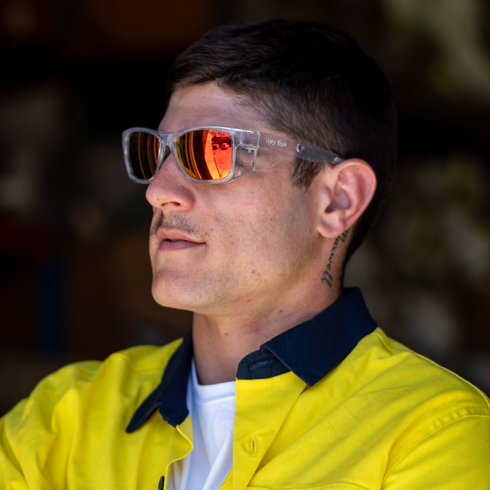 Man wearing Ugly Fish safety sunglasses with mirror lenses and a yellow jacket with a blurred background