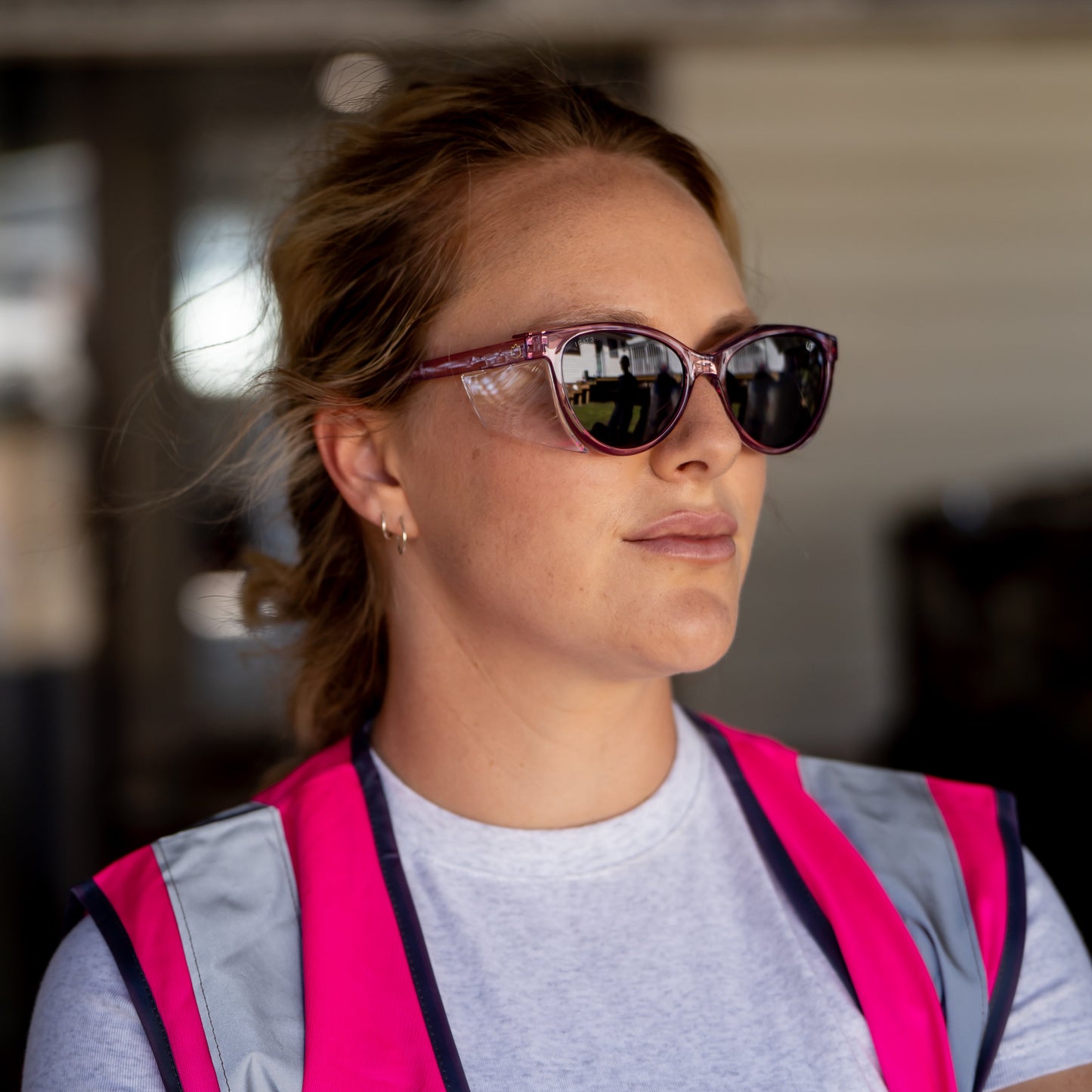 Person wearing Ugly Fish Safety sunglasses and a pink vest in an indoor setting