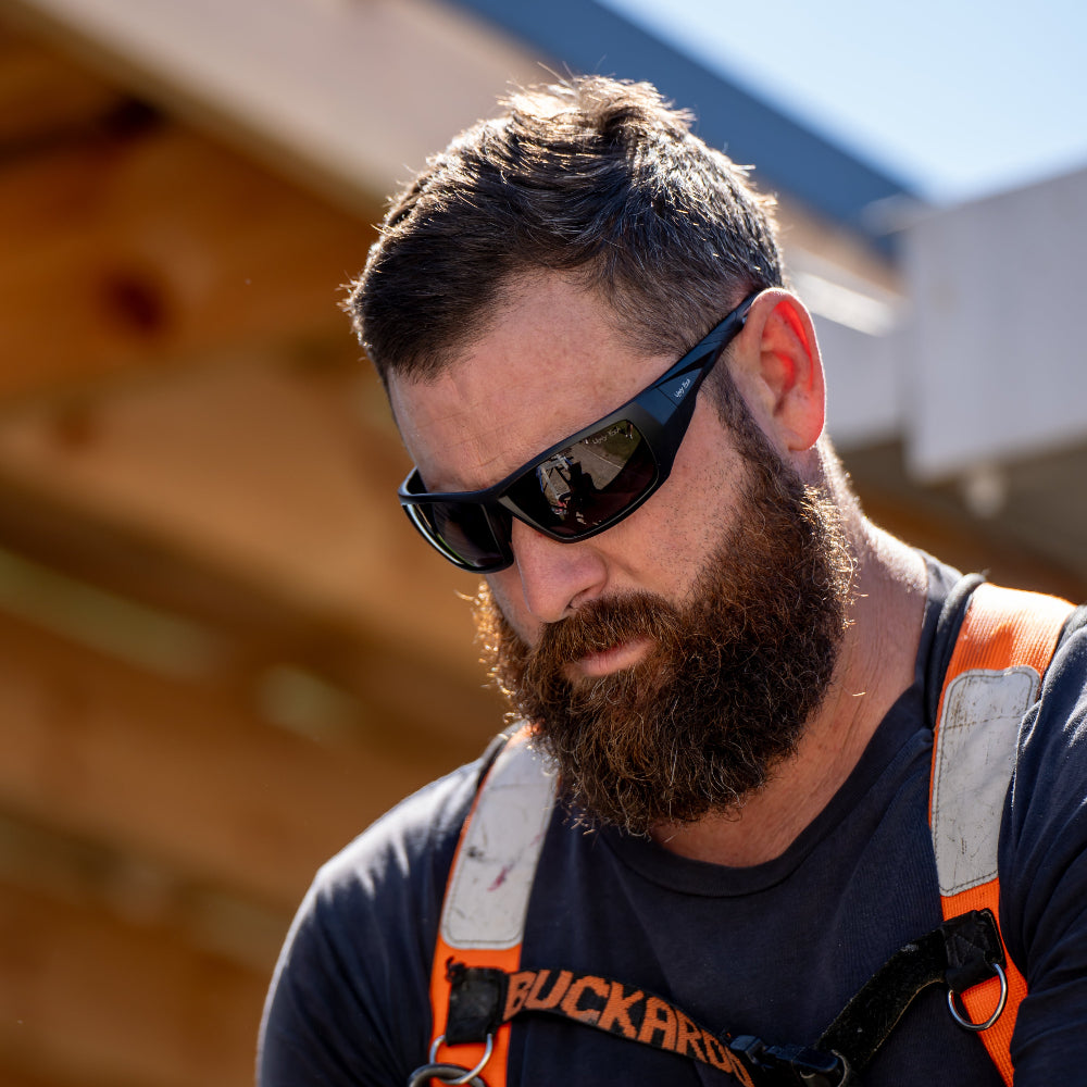 Man wearing Ugly Fish Safety sunglasses and a safety harness with a blurred background
