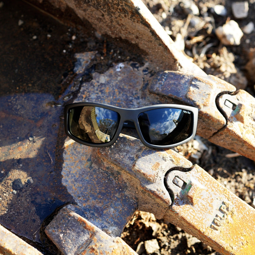 Ugly Fish Safety sunglasses on a rusty metal surface with a natural background