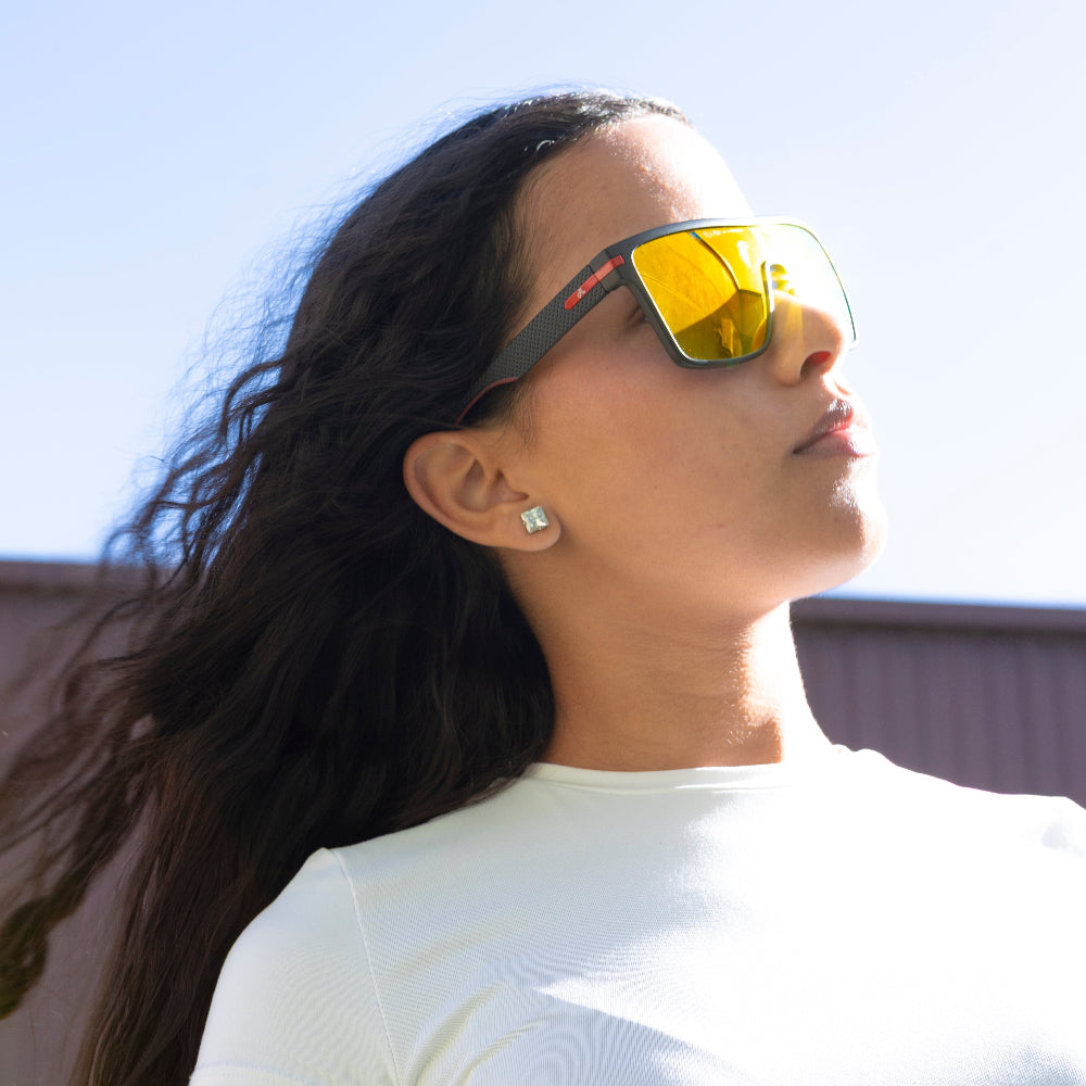 Woman wearing Sage Retro reflective sunglasses against a clear blue sky