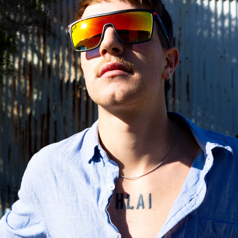Person wearing Sage Retro reflective sunglasses and a blue shirt with tattoo.