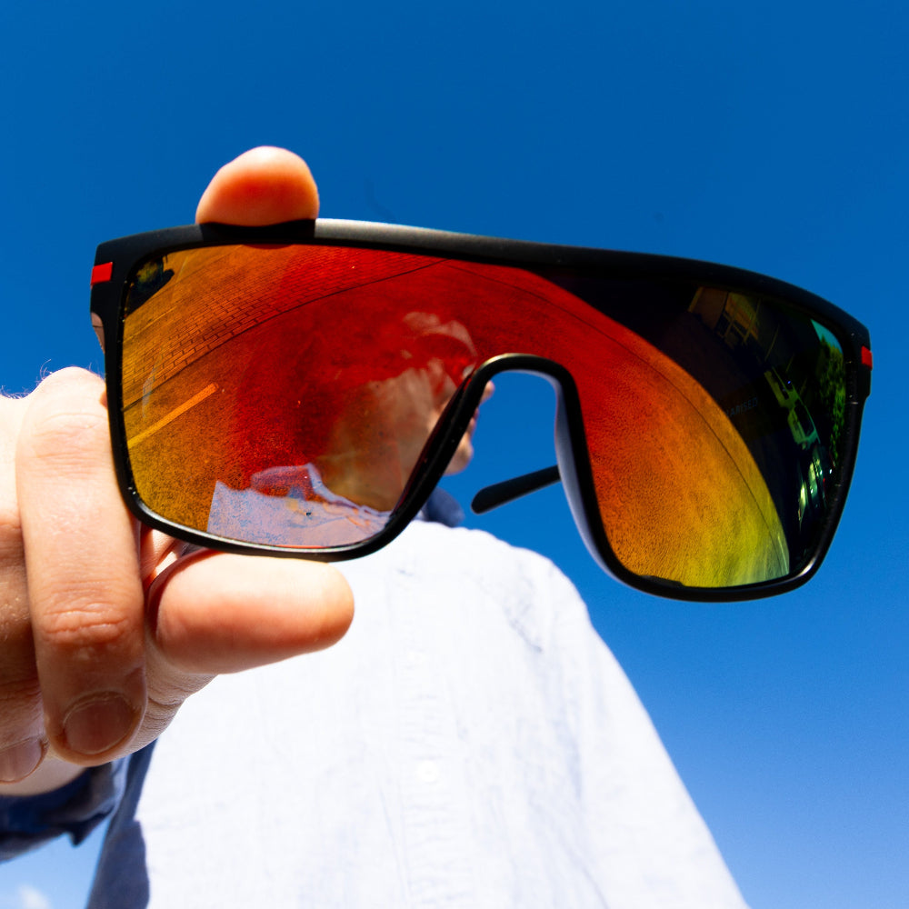 Person holding a pair of Sage Retro sunglasses against a blue sky