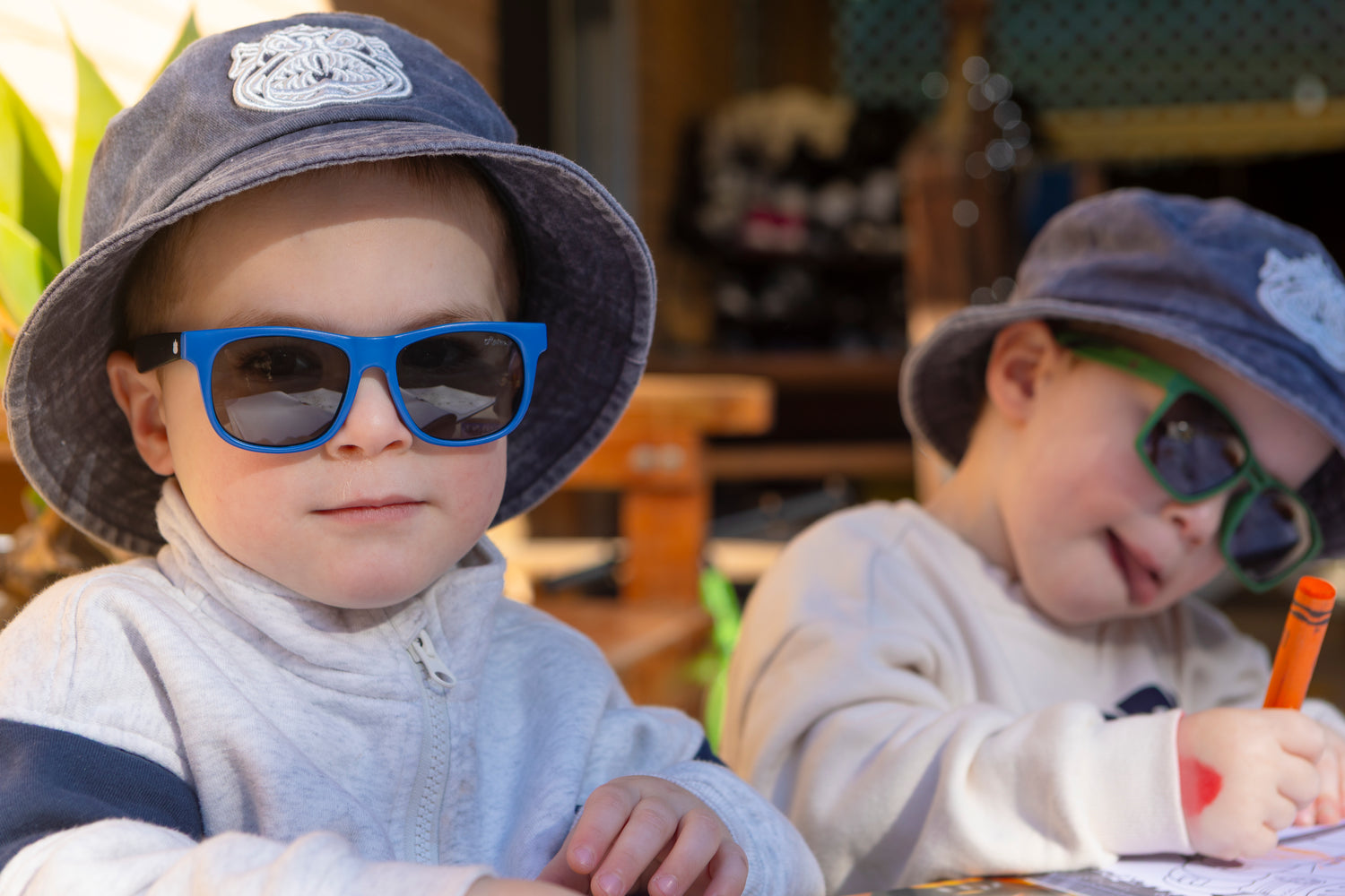 Two children wearing hats and sunglasses in an indoor setting.