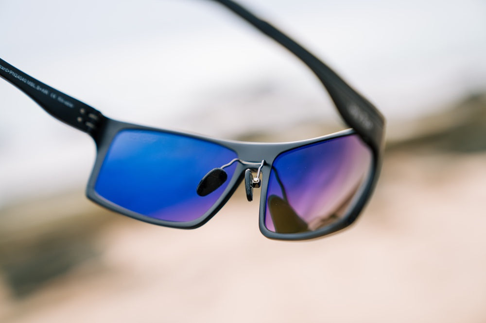 Close-up of Ugly Fish metal sunglasses with blue lenses on a blurred background