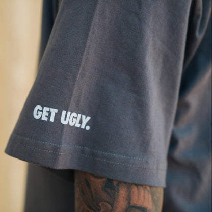 Grey shirt with 'GET UGLY.' text on a blurred background