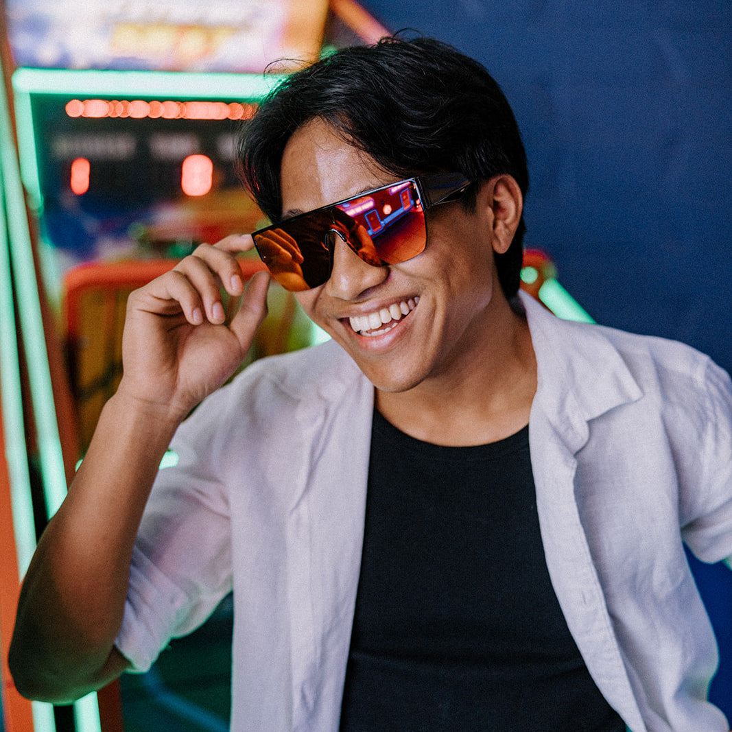 Person wearing Bohemian Retro sunglasses in front of an arcade machine