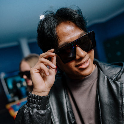 Man wearing Rogue sunglasses and a black leather jacket in a room with blue walls.