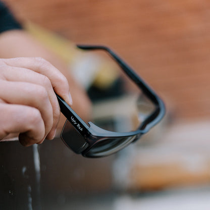 Person holding black Freestone safety sunglasses with Ugly Fish branding against a blurred background
