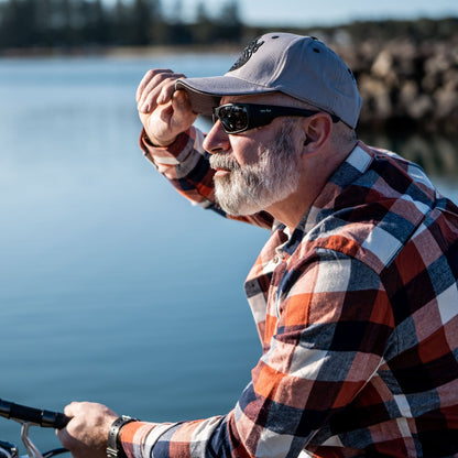 Man wearing Ugly Fish polarised sunglasses and a cap by a body of water