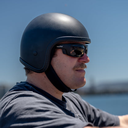 Man wearing a black helmet and sunglasses with a blurred background