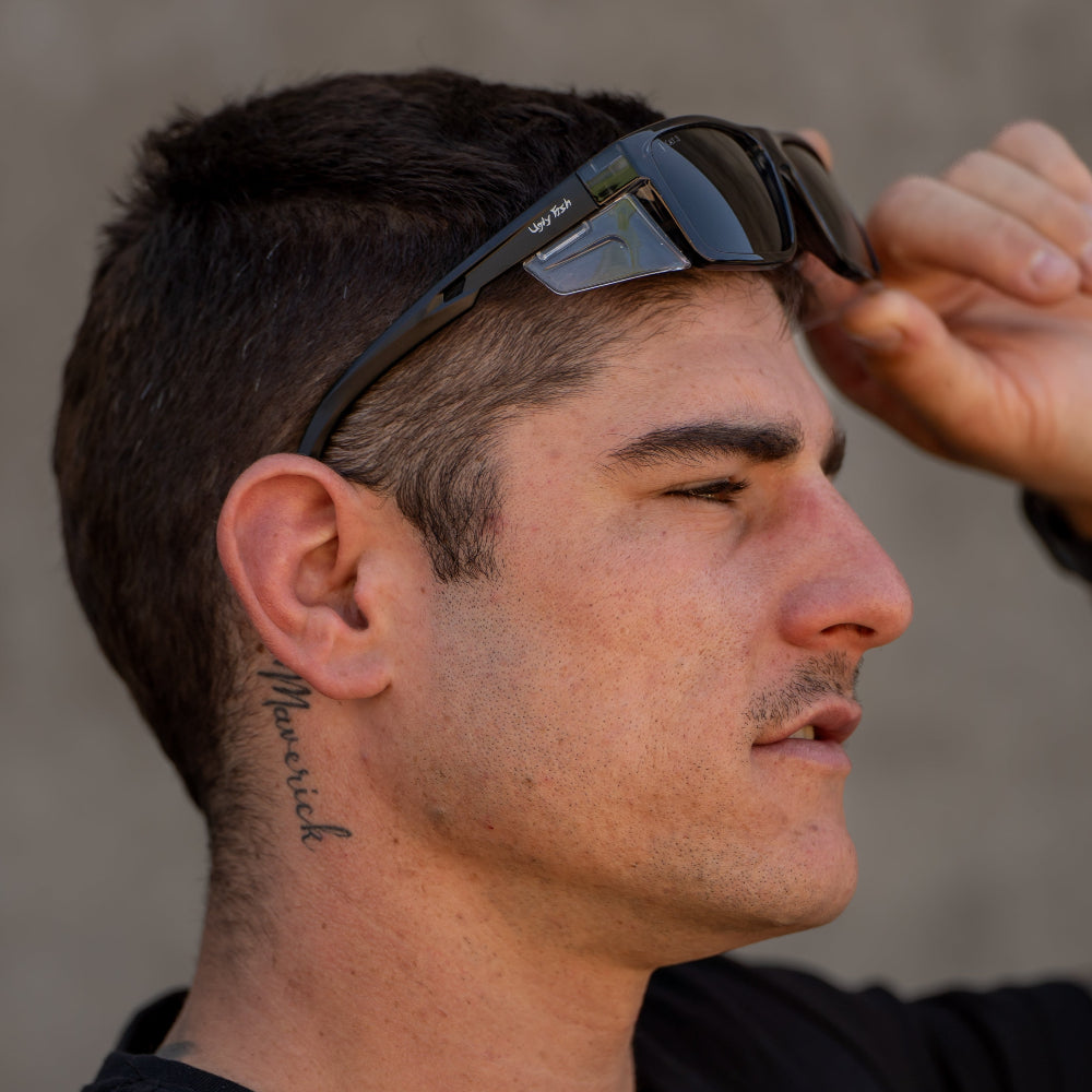 Man adjusting safety sunglasses on his head with a neutral background