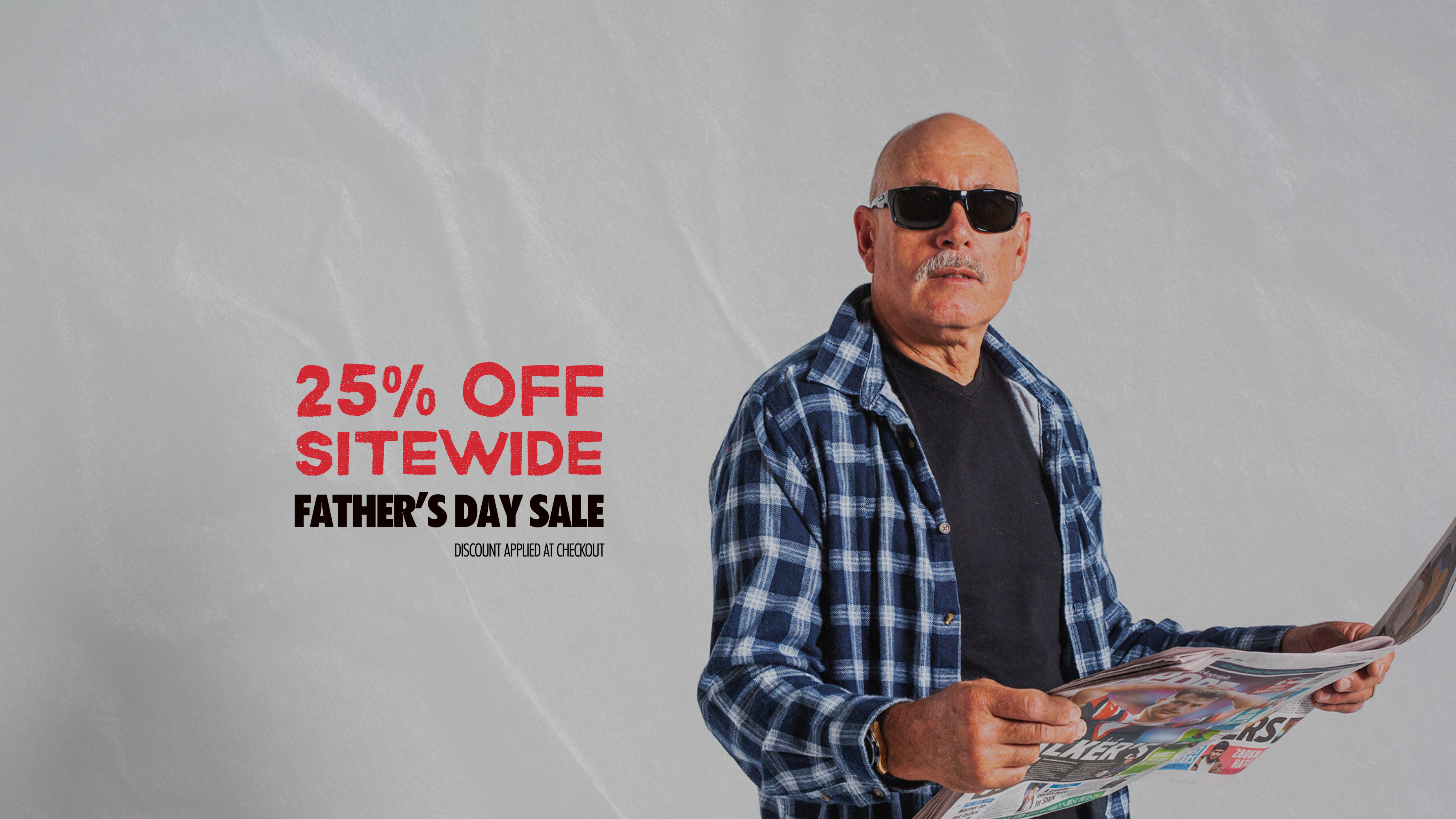 Man holding a newspaper with a Father's Day sale advertisement on a gray background